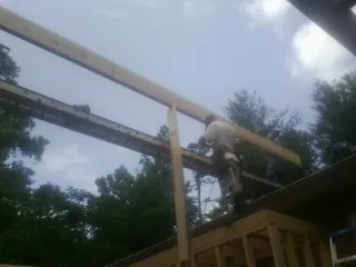 Carpenter setting a ridge beam over a new addition frame — Ice Dam Removal by Roofing Brothers in Villard