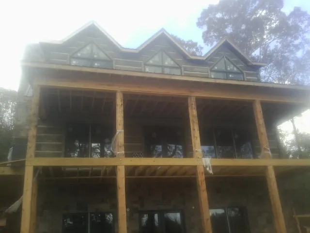 Dormers and porch framing on a large log home under construction — Roof Coating work by our crew in Villard