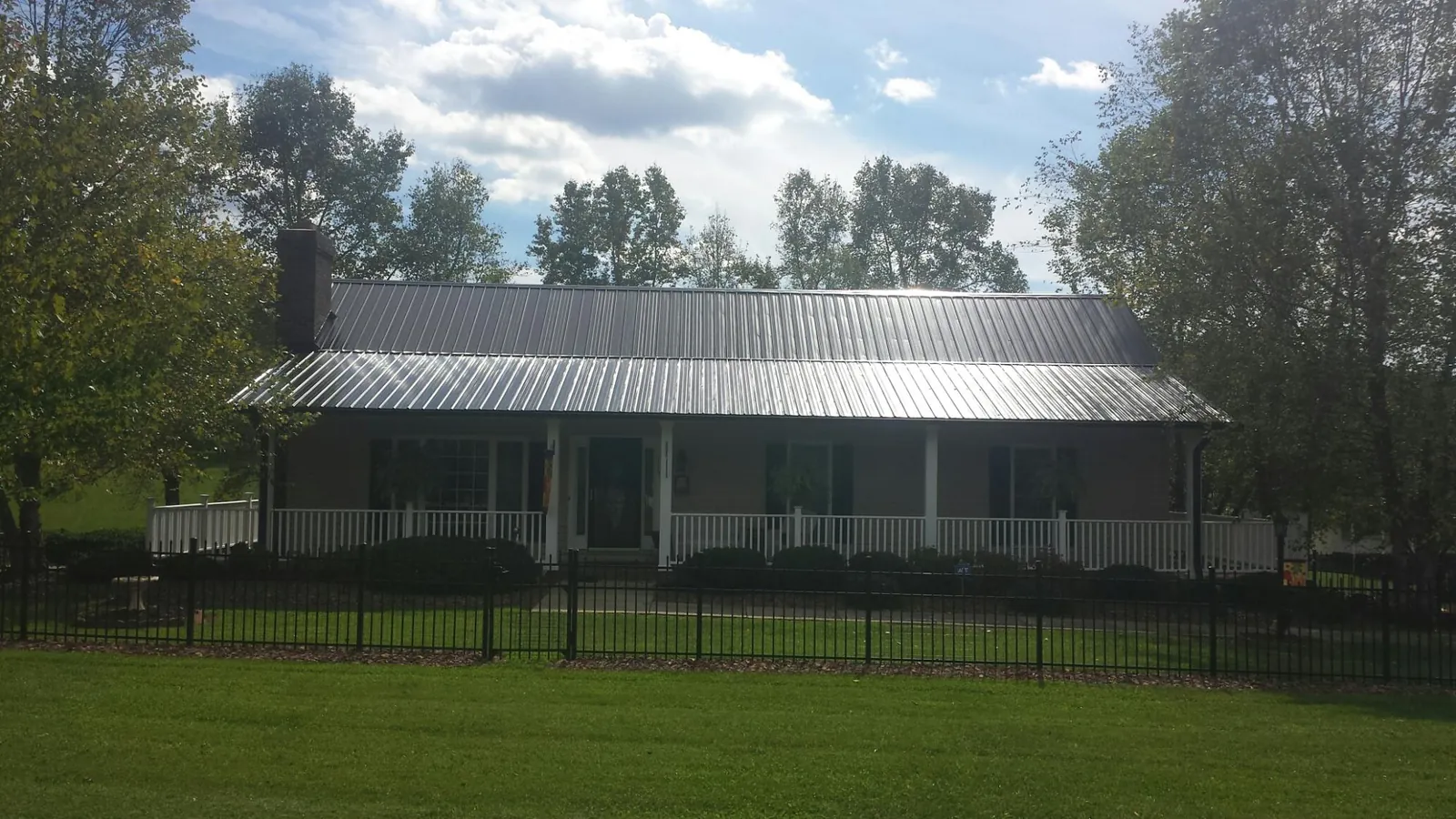 Gray metal roof on a brick ranch with a full width front porch — Gutter Guard Installation work by our crew in Villard